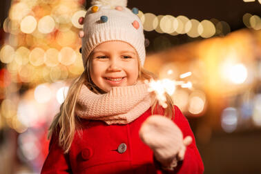 Tyttö ulkona tähtisadetikku kädessä.