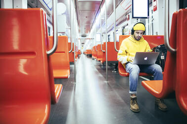 Mies käyttää läppäriä metrossa.