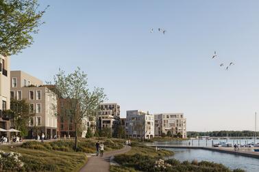 Vehreän rannan vieressä on virkistysreitti ja kerrostaloja.