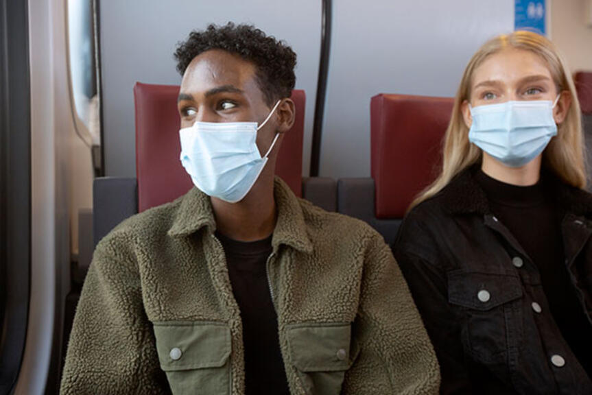 Kaksi nuorta maskit kasvoillaan lähijunassa. Kaksi nuorta maskit kasvoillaan lähijunassa.