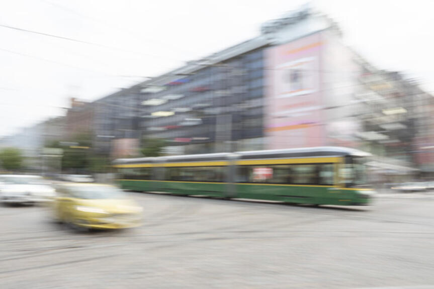 Keskustassa auto ja raitiovaunu kauppakeskuksen edustalla.