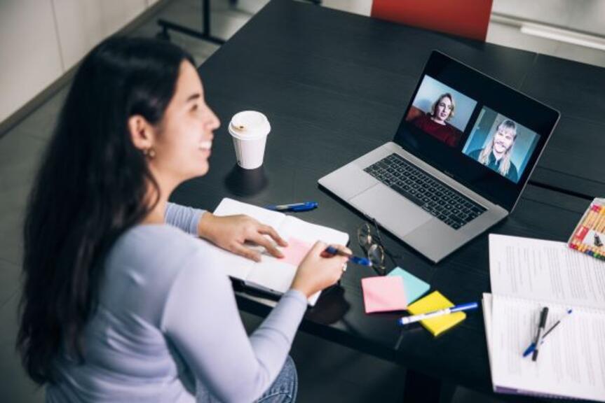 Nainen istuu pöydän ääressä kannettava tietokone edessään. Nainen istuu pöydän ääressä kannettava tietokone edessään.