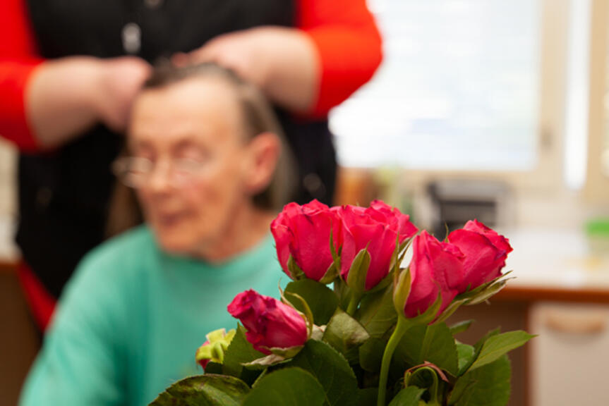 Hoitaja letittää asukkaan tukkaa. Hoitaja letittää asukkaan tukkaa.