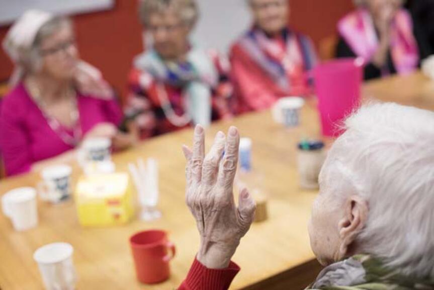 Joukko ikäihmisiä pöydän äärellä. Joukko ikäihmisiä pöydän äärellä.