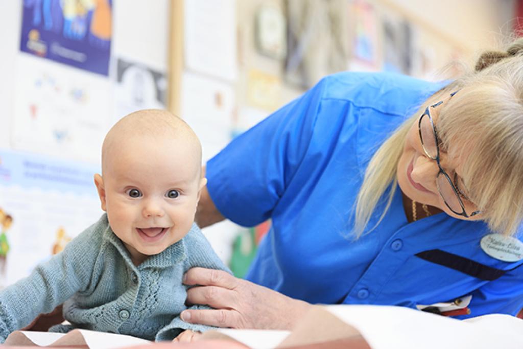 Vauva Teo Hänninen suhtautuu rauhallisesti neuvolakäyntiinsä. Hymy on herkässä senkin vuoksi, että terveydenhoitaja Kaisu-Liisa Hänninen on hänelle tuttu.