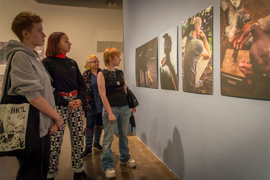 Helsingin kuvataidelukion opiskelijoita valokuvanäyttelyssä opettajansa kanssa.