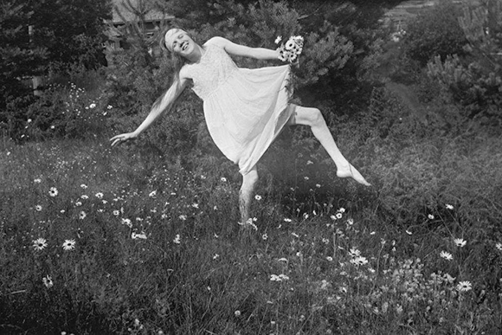 Nuori Martta Bröyer tanssii kukkivalla niityllä.
