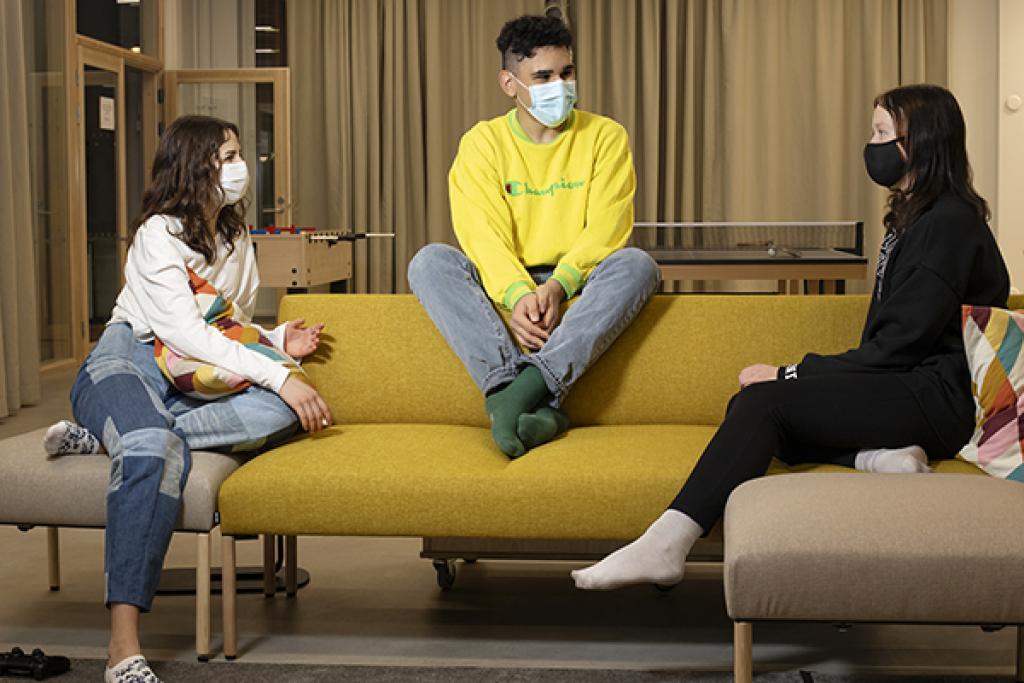 Kolme nuorta istuu sohvalla maskit kasvoillaan nuorisotalolla
