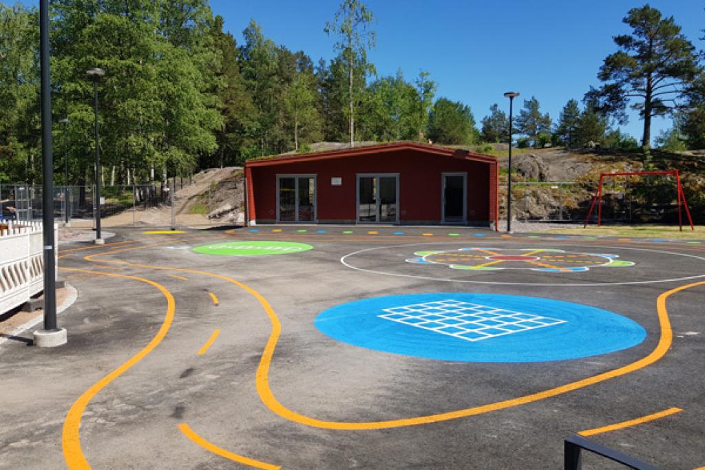 Osa leikkipuiston alueesta on asfaltoitua. Pintaan on maalattu polkupyörärata lapsia varten. 