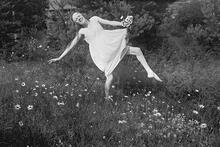 Nuori Martta Bröyer tanssii kukkivalla niityllä.
