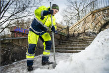Talvikunnossapidon työntekijä hakkaamassa jäätä pois kulkuväylältä.